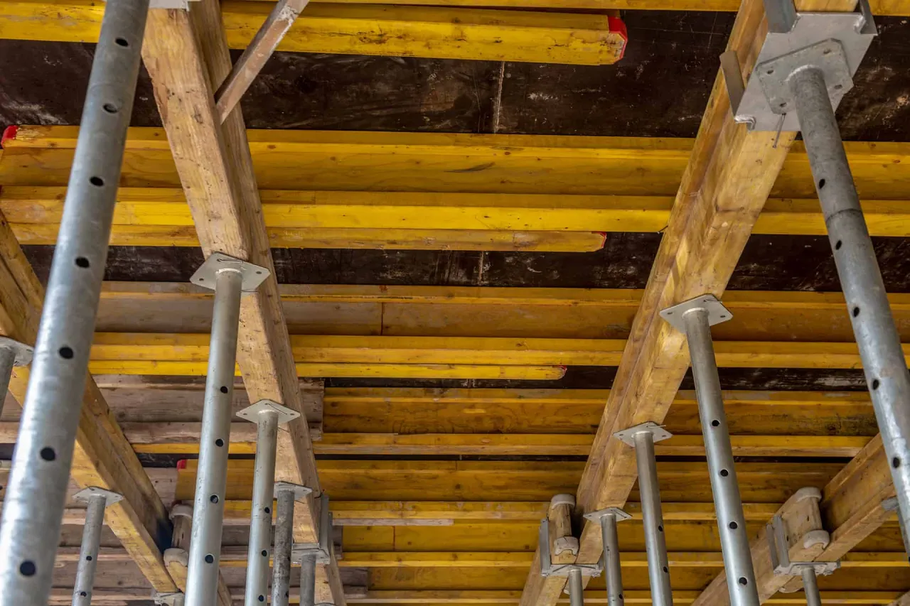 Konstrukcja tymczasowa, podpora stropu. Drewniane belki i metalowe podpory tworzą szalunek, czekając na beton.