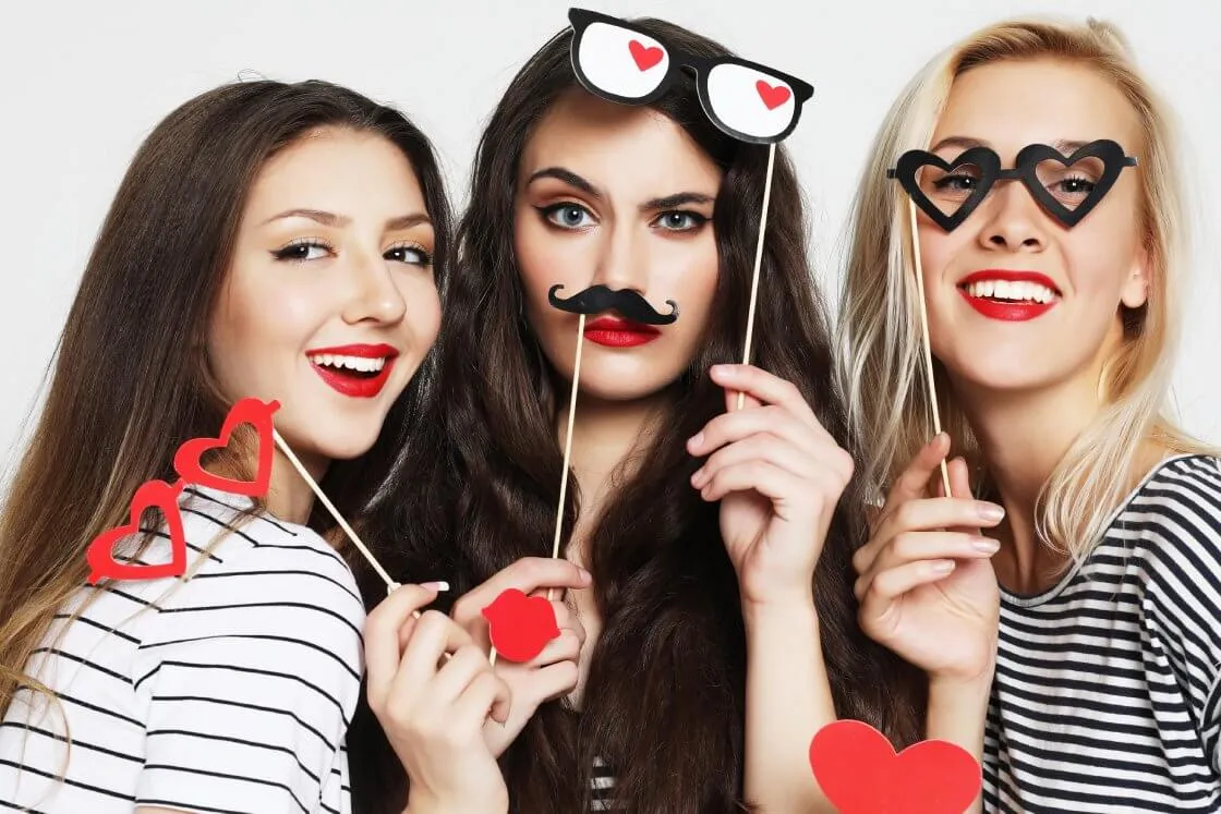 ludzie bawiący się w fotobudce z gadżetami