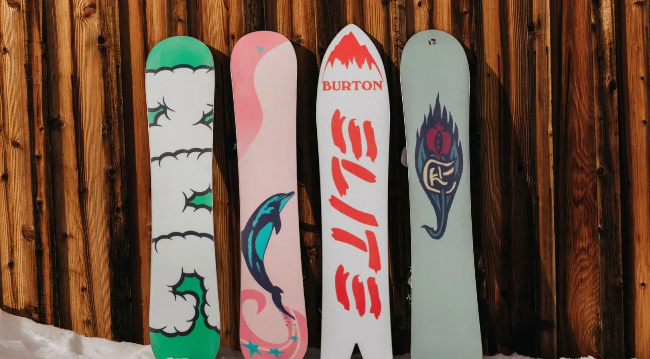 Cztery deski snowboardowe z różnymi grafikami: delfin, góry, płomienie i wzór. Zastanawiasz się, ile kosztuje snowboard?