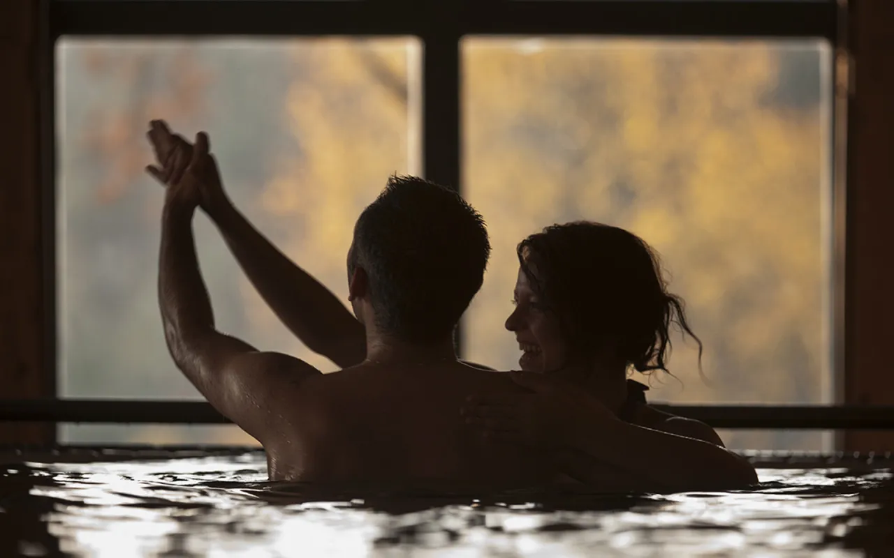 Para spędza romantyczny weekend w spa. Kobieta obejmuje mężczyznę, oboje cieszą się wsp&oacute;lnym czasem w wodzie.