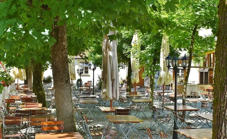 Gem&uuml;tlicher Au&szlig;enbereich eines Restaurants unter einem gro&szlig;en Baum