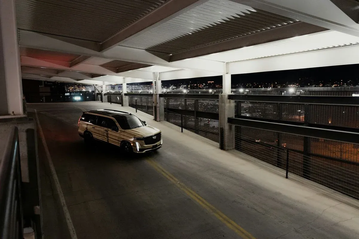 Złoty Cadillac Escalade na parkingu nocą. Zastanawiasz się, ile kosztuje wynajem samochodu tej klasy?