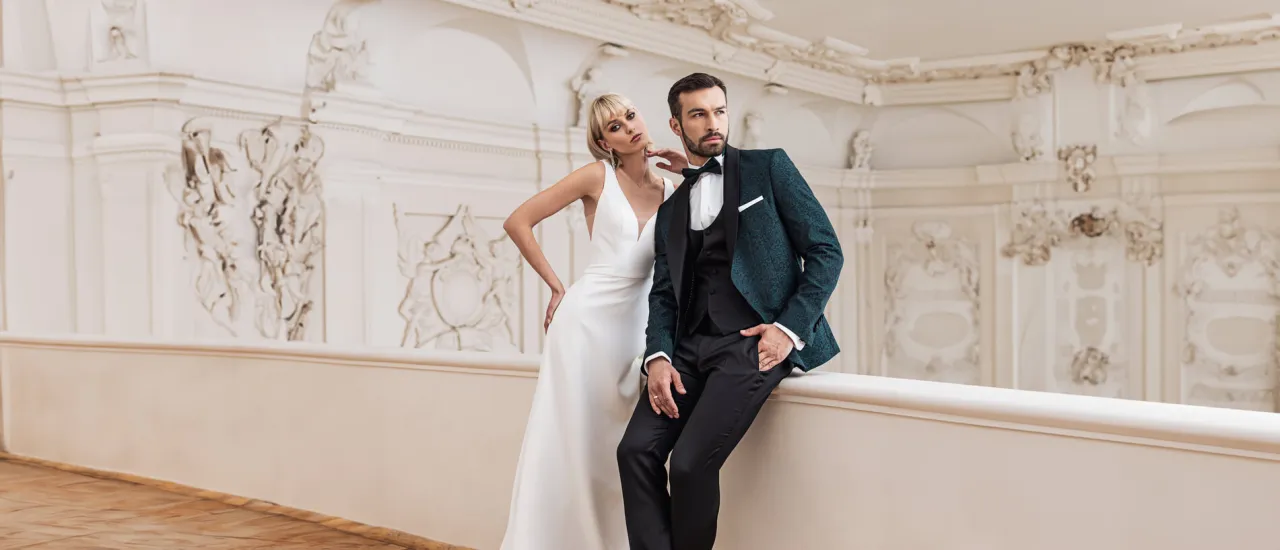 Elegancka para w stylizacjach idealnych na wiecz&oacute;r. Ona w białej sukni, on w zielonym, wzorzystym garniturze. Doskonała inspiracja, co założyć do teatru.