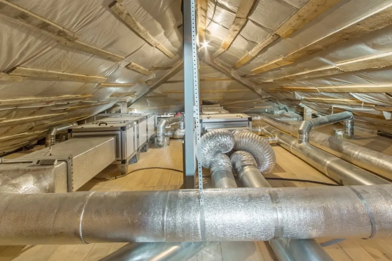 System wentylacji na poddaszu z metalowymi kanałami i izolacją. Zastanawiasz się, czym ocieplić rury wentylacyjne? Tutaj widzisz przykłady.