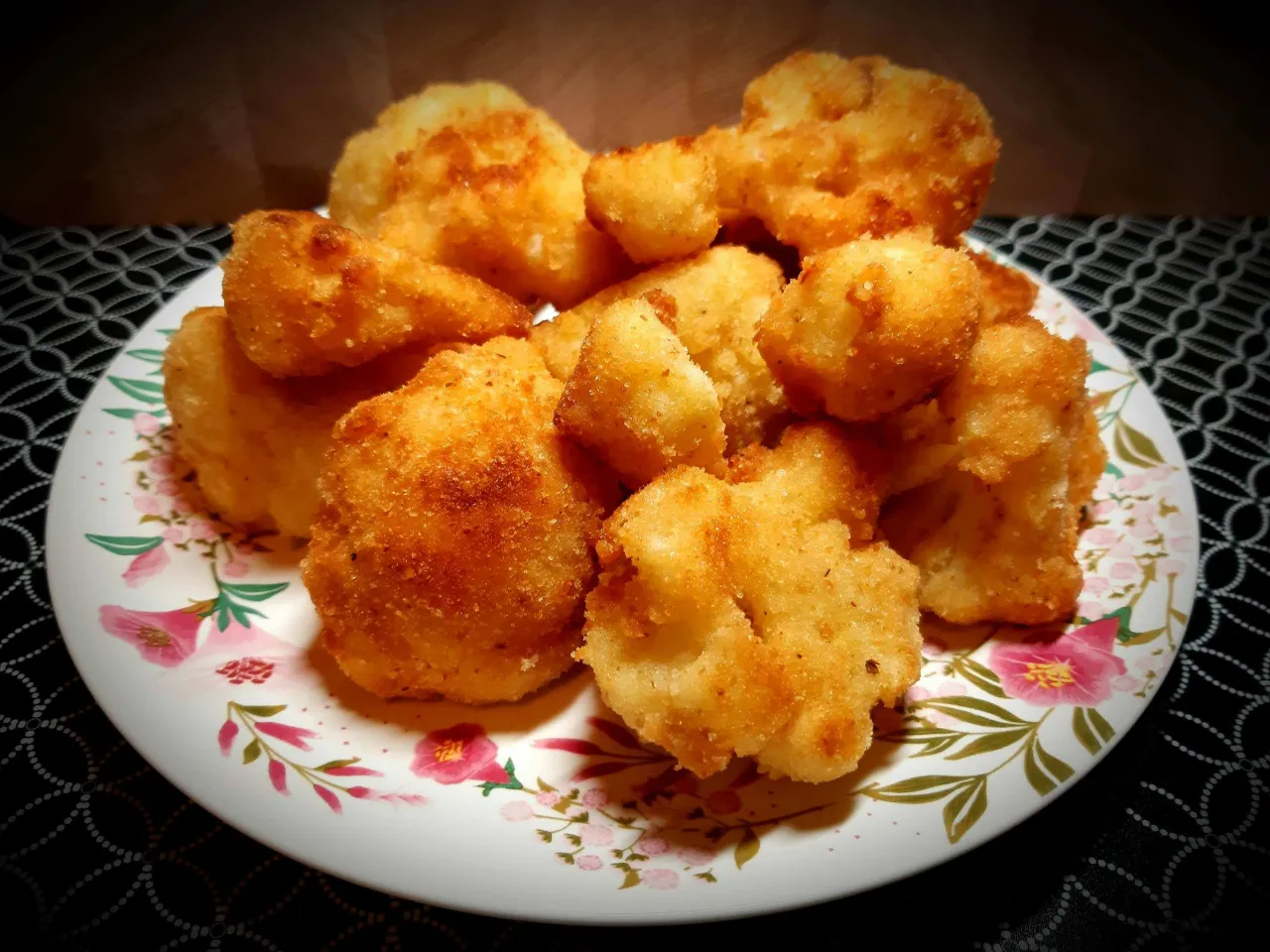 Chrupiący kalafior w panko, złocisty i apetyczny, ułożony na talerzu z kwiatowym wzorem.