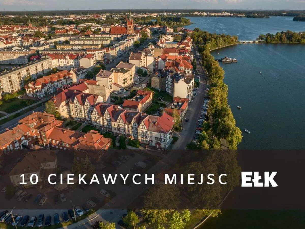 Malownicze miasto nad jeziorem, idealne miejsce, by odkryć, co zwiedzić w Ełku. Widok z lotu ptaka na zabudowania i wodę.