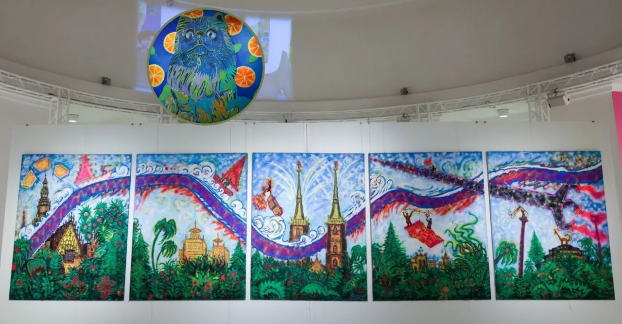 Kolorowe obrazy w muzeum sztuki Wrocław: fantastyczne miasto z wieżami, latającymi ludźmi i niebieskim kotem z pomarańczami.