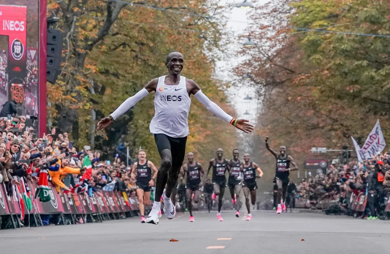 Eliud Kipchoge przekracza linię mety, świętując swój historyczny bieg. Maraton ma 42,195 km.