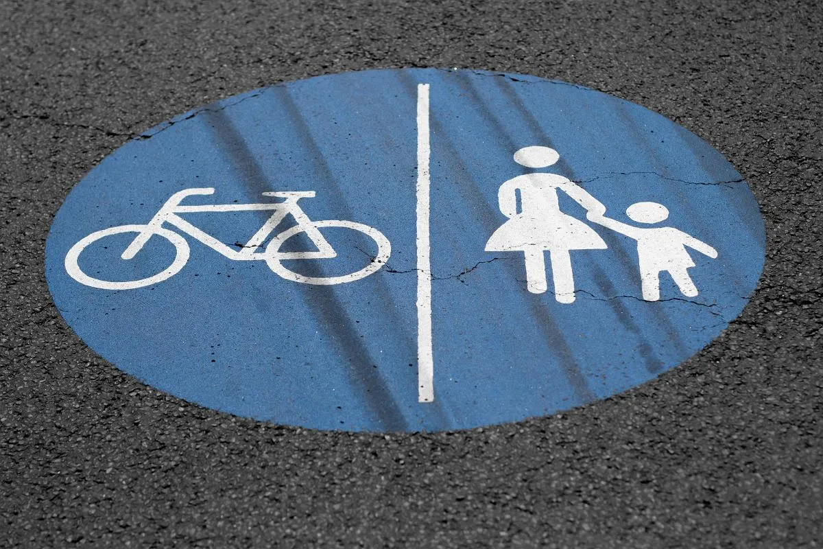 Rowerzysta ustępujący pieszym na chodniku