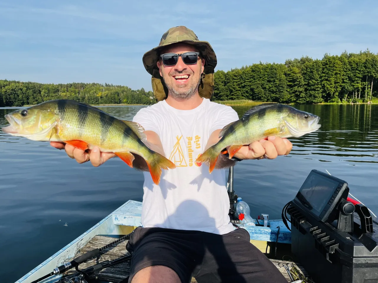 Szczęśliwy wędkarz z dwoma okoniami na jeziorze. Wędka feeder do łowienia ryb na spokojnych wodach.