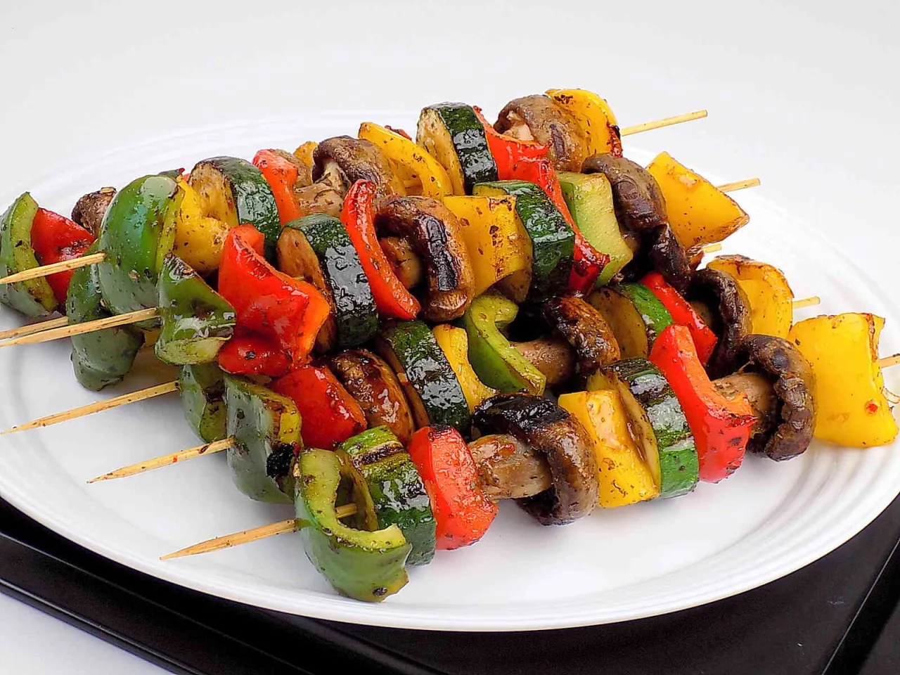 Kolorowe warzywa na patykach: papryka, cukinia i pieczarki. Idealny przykład, jak zrobić szaszłyka na grilla.