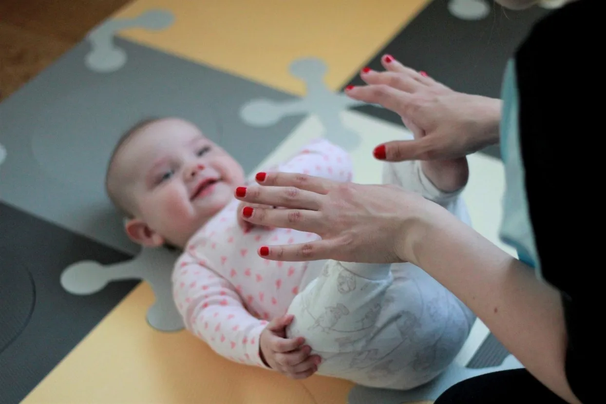 rodzic bawi się z niemowlęciem na brzuchu zabawkami