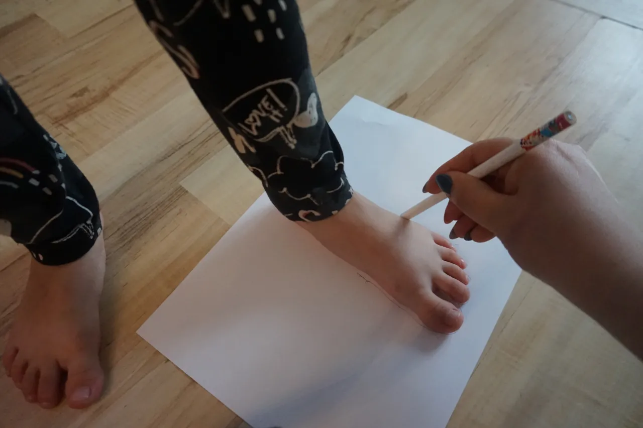 Dziecko mierzy stopę na kartce papieru