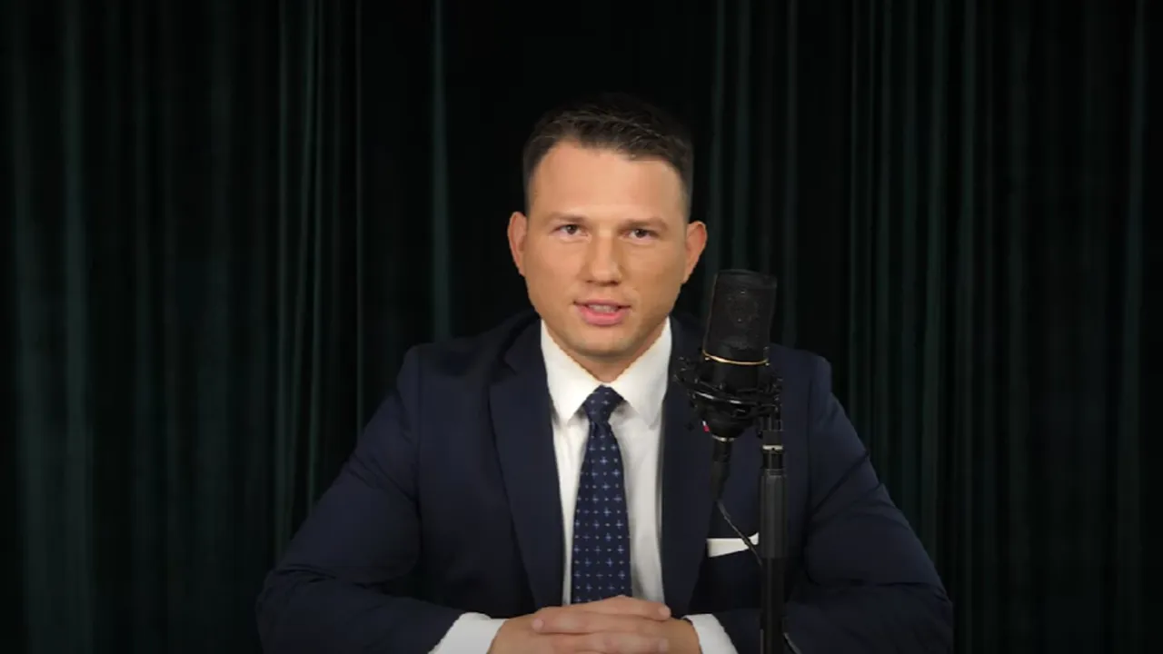 Mężczyzna w garniturze przed mikrofonem, dyskutuje o tym, ile mentzen ma btc.