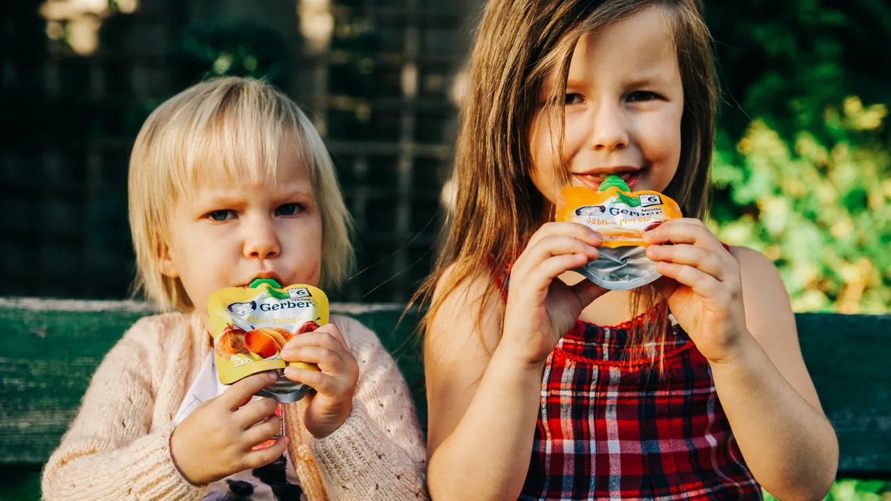 Dziecko jedzące mus owocowy z tubki i świeże owoce