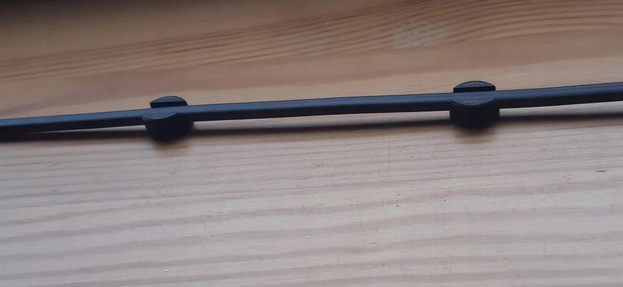 Dwa czarne klipsy służą do mocowania przewod&oacute;w elektrycznych do drewna, zapewniając porządek.