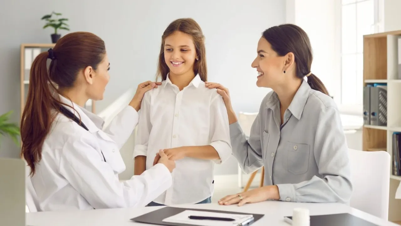 Lekarka uspokaja młodą pacjentkę i jej mamę. Dowiedz się, jak się umówić do ginekologa na NFZ.