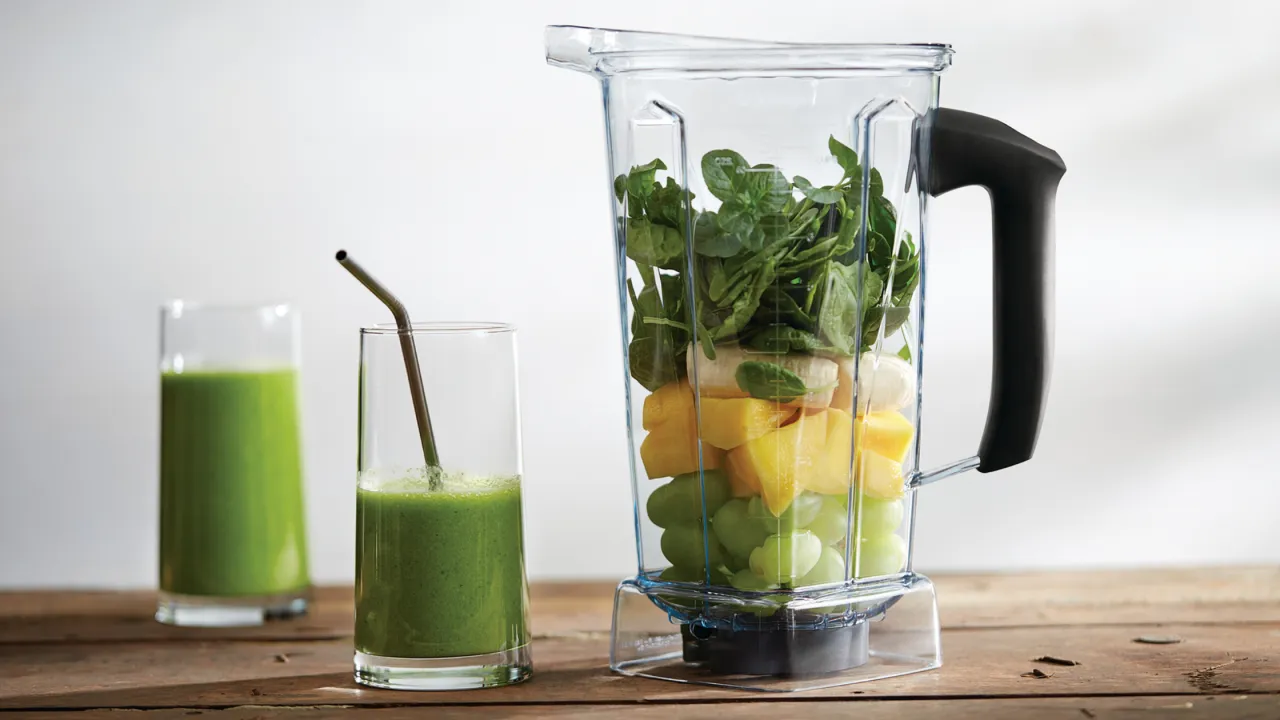 osoba przygotowująca zielony koktajl w blenderze