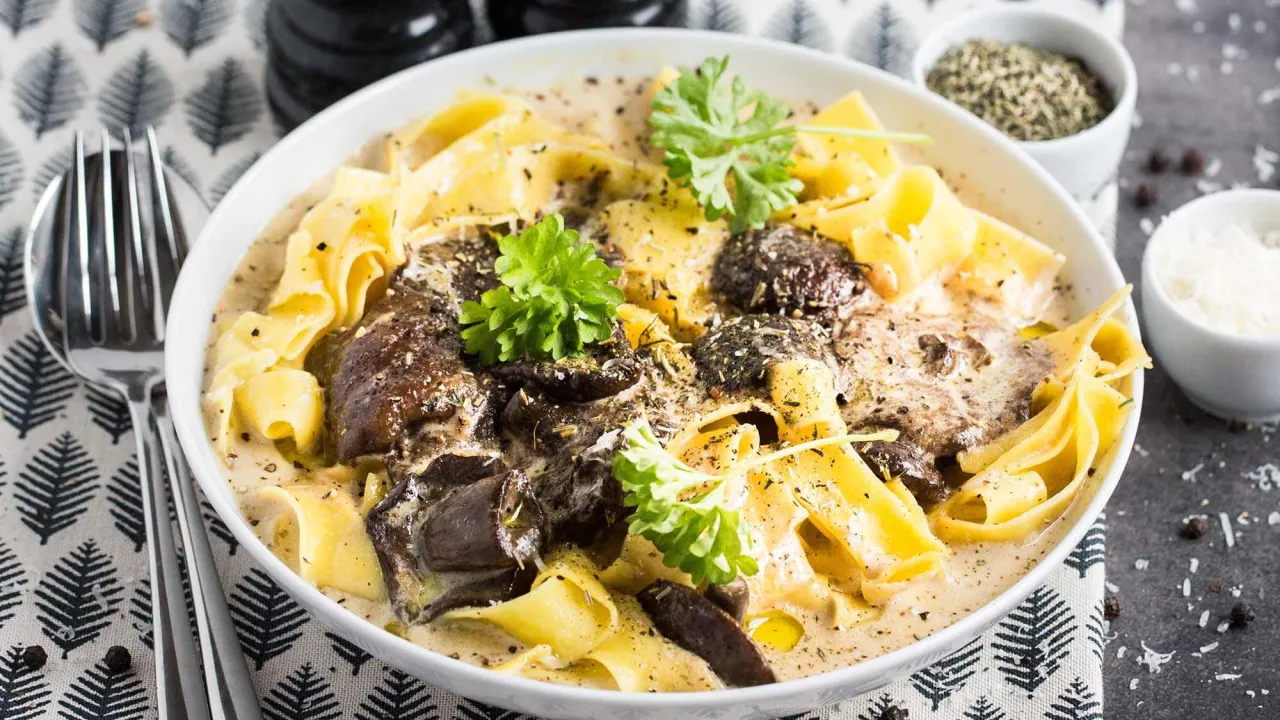 Makaron z grzybami w śmietanowym sosie, posypany ziołami. Idealne jakie przyprawy do grzybów w śmietanie? Zobacz!