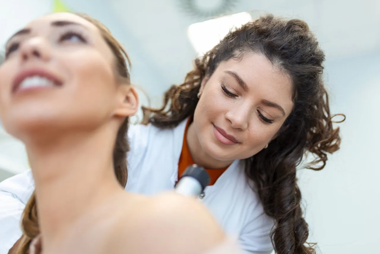 Dermatologe untersucht die Gesichtshaut eines Patienten mit einem Dermatoskop