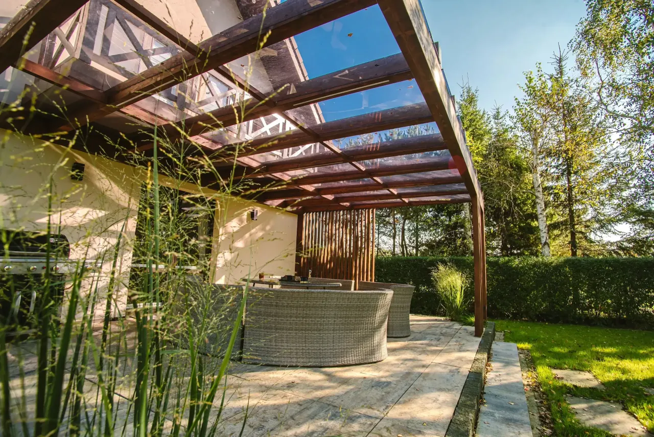 Nowoczesny taras z drewnianą pergolą i przeszklonym dachem. Czy potrzebne pozwolenie na budowę tarasu? Sprawdź przepisy.