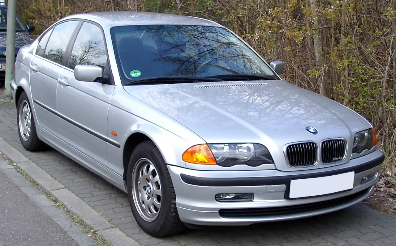 Srebrne BMW E46, produkowane w latach 1997-2006, zaparkowane przy chodniku.