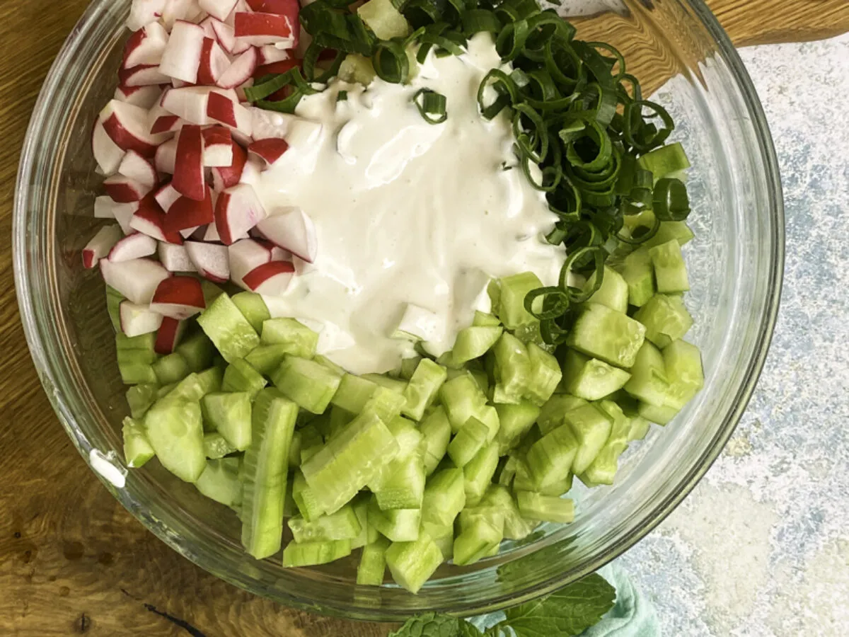 Świeża surówka z rzodkiewki, ogórka i szczypiorku w kremowym sosie, idealna do obiadu.