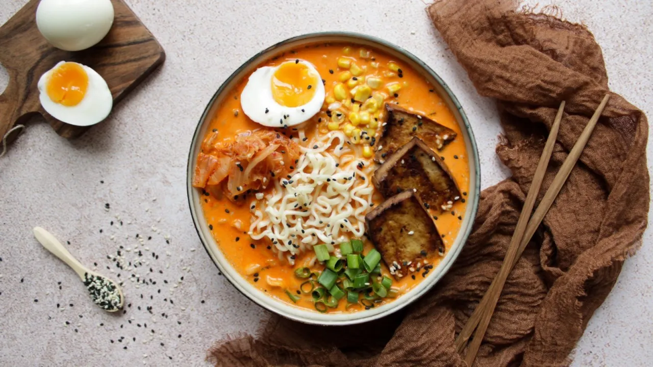 Jak zrobić ramen z zupki chińskiej? Miska pełna pyszności: makaron, jajko na miękko, tofu, kukurydza, kimchi i szczypiorek.