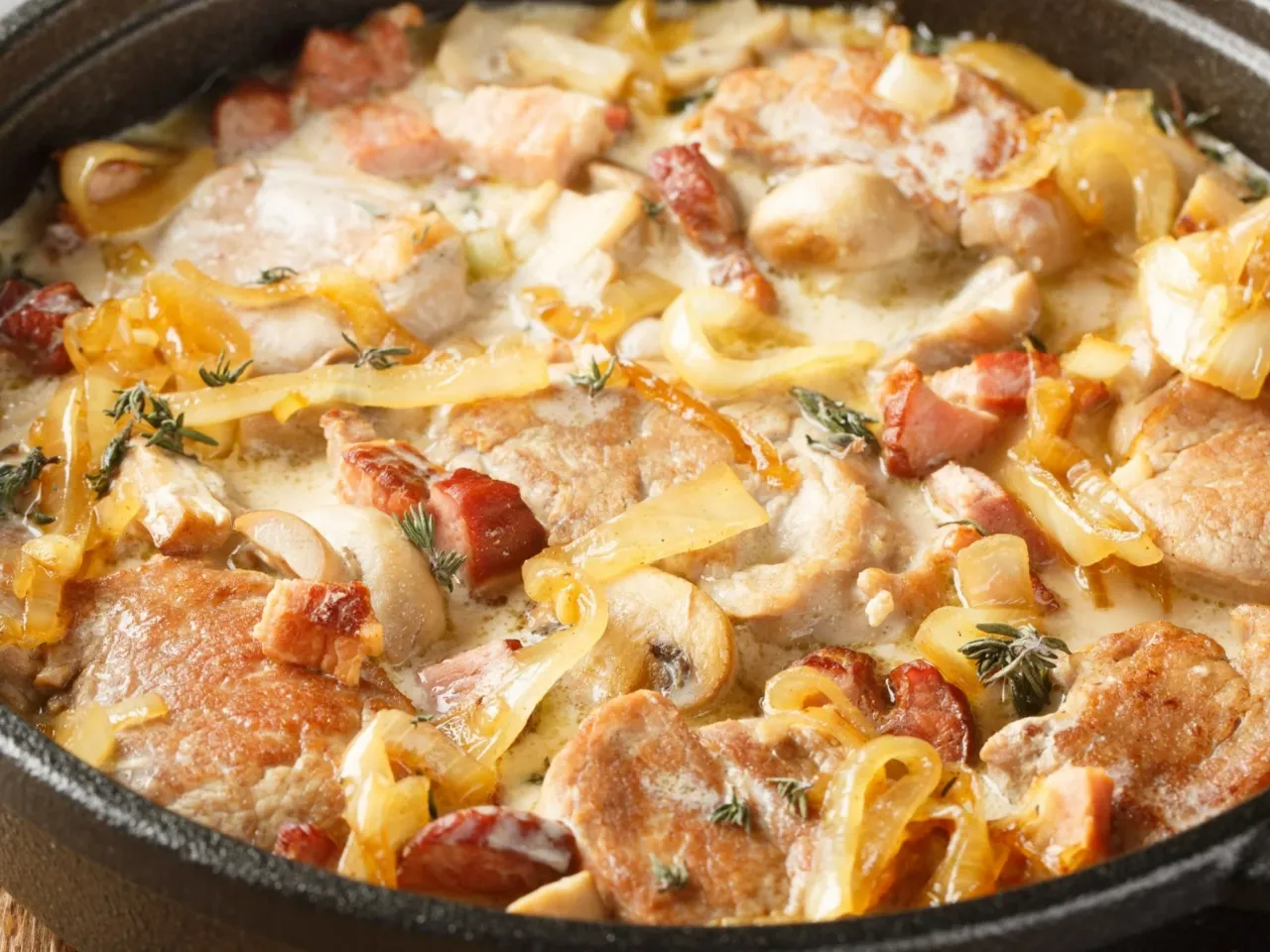 Jak zrobić poledwiczke na obiad? Danie z kawałkami wieprzowiny, boczku, cebuli i pieczarek w kremowym sosie.