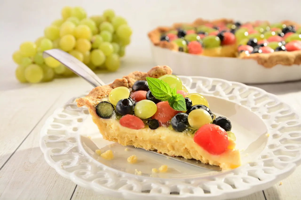 Sernik z owocami na kruchym spodzie, z winogronami, bor&oacute;wkami i arbuzem. Idealny deser, gdy zastanawiasz się, co można zrobić z ugotowanego budyniu.