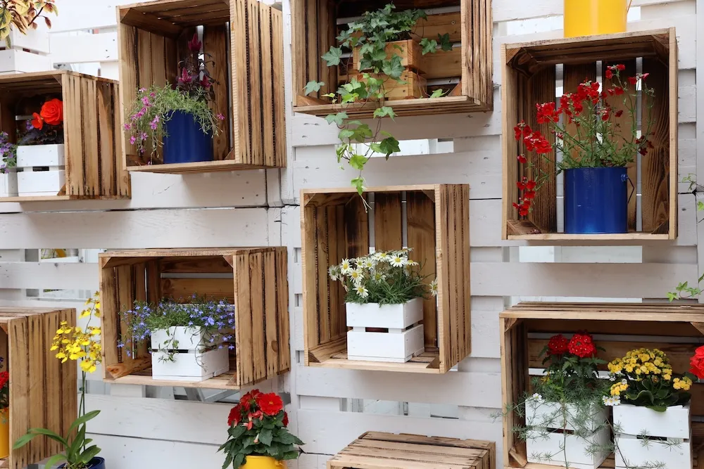 kwietnik z palet pełen kolorowych kwiatów i ziół