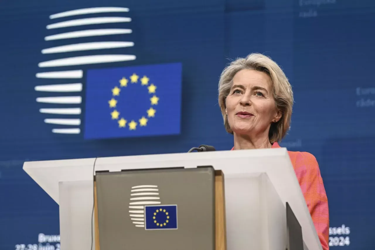 Ursula von der Leyen, kt&oacute;ra zatwierdziła Zielony Ład, przemawia na tle flagi UE.