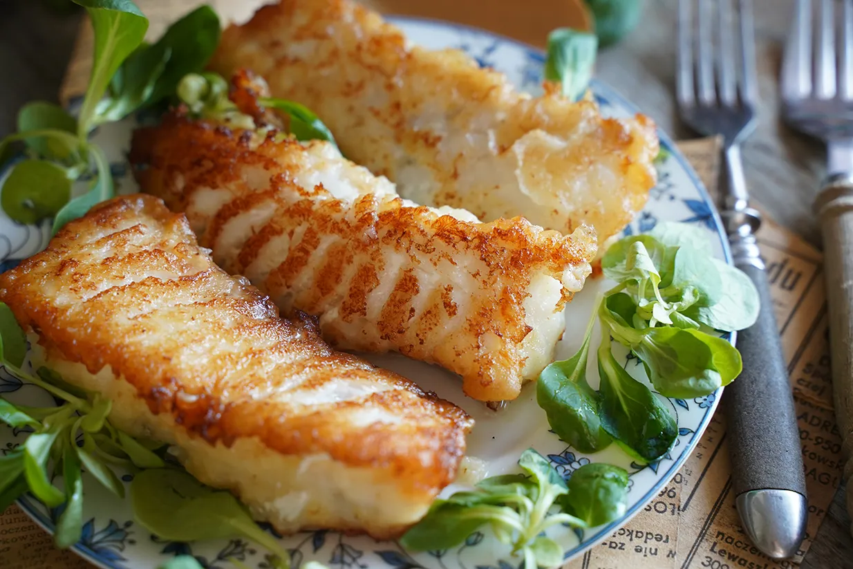 świeża smażona ryba z dodatkami na talerzu nad morzem