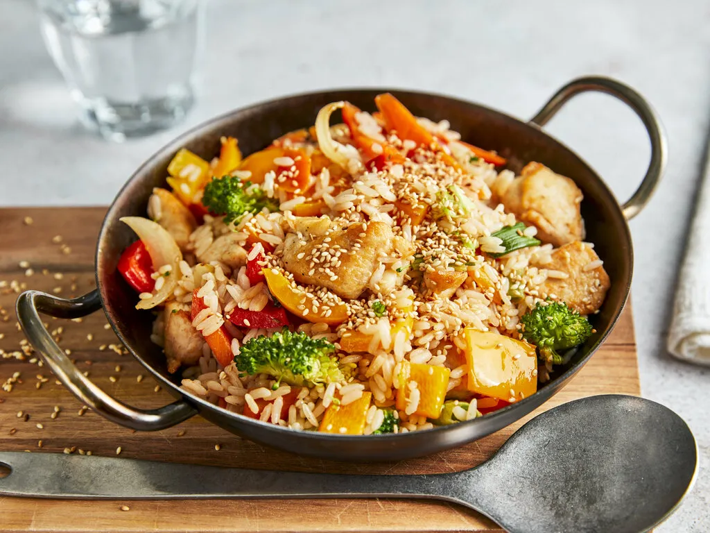 Leckeres Pfannengericht mit Reis und H&auml;hnchen in einer gusseisernen Pfanne