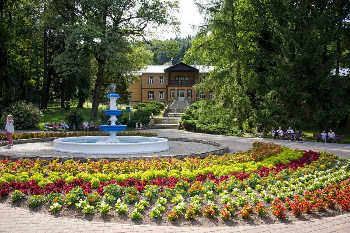 Kolorowe rabaty kwiatowe i fontanna przed jednym z rymanów zdrój sanatoria.