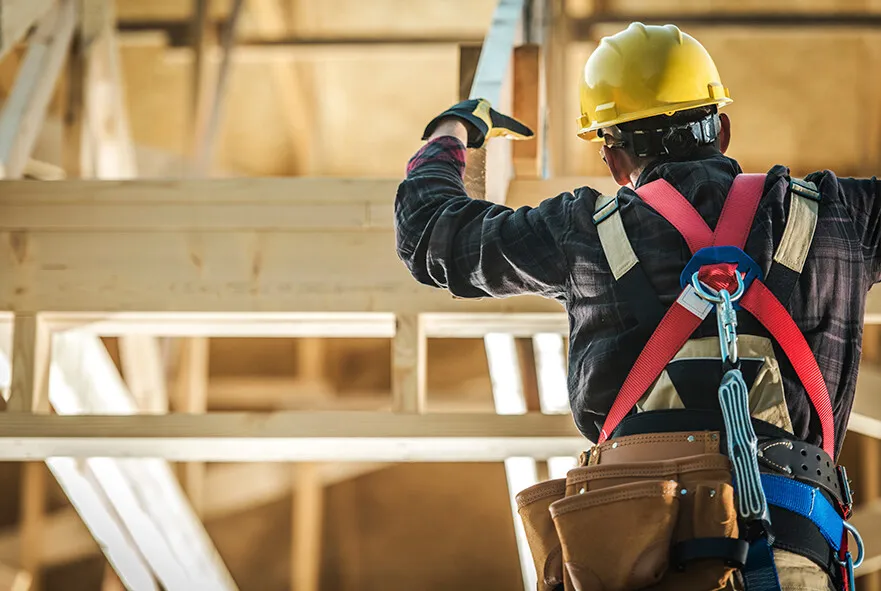 dekarz w kasku i uprzęży na dachu