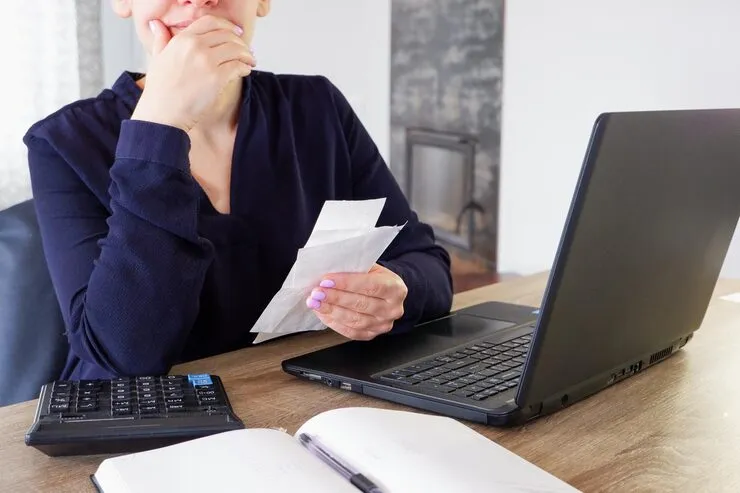 Młoda osoba pracująca z laptopem i kalkulatorem