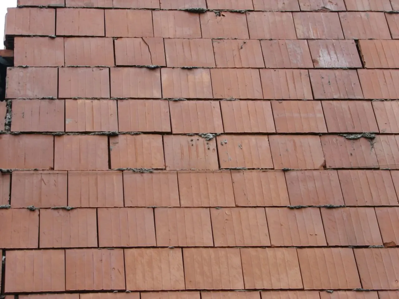 Zbliżenie na murowanie ścianek działowych z cegieł ceramicznych. Widać pionowe rowki na powierzchni cegieł i nierówności zaprawy.