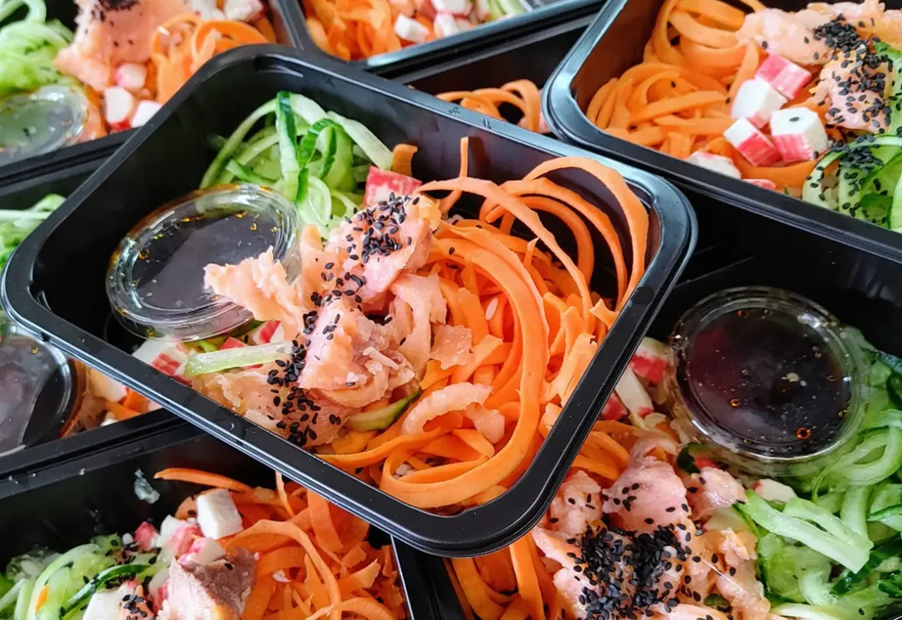 Kolorowe dania z łososiem, marchewką i og&oacute;rkiem w pojemnikach. Dowiedz się, jak podgrzewać catering dietetyczny, by zachować świeżość i smak.