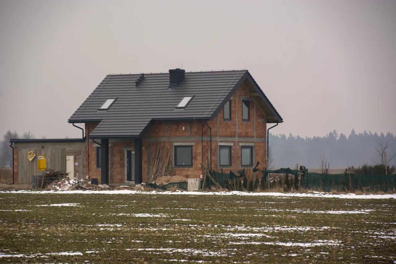 Dom w budowie, z cegły, z szarym dachem. Zastanawiasz się, jak długo jest ważne pozwolenie na budowę?