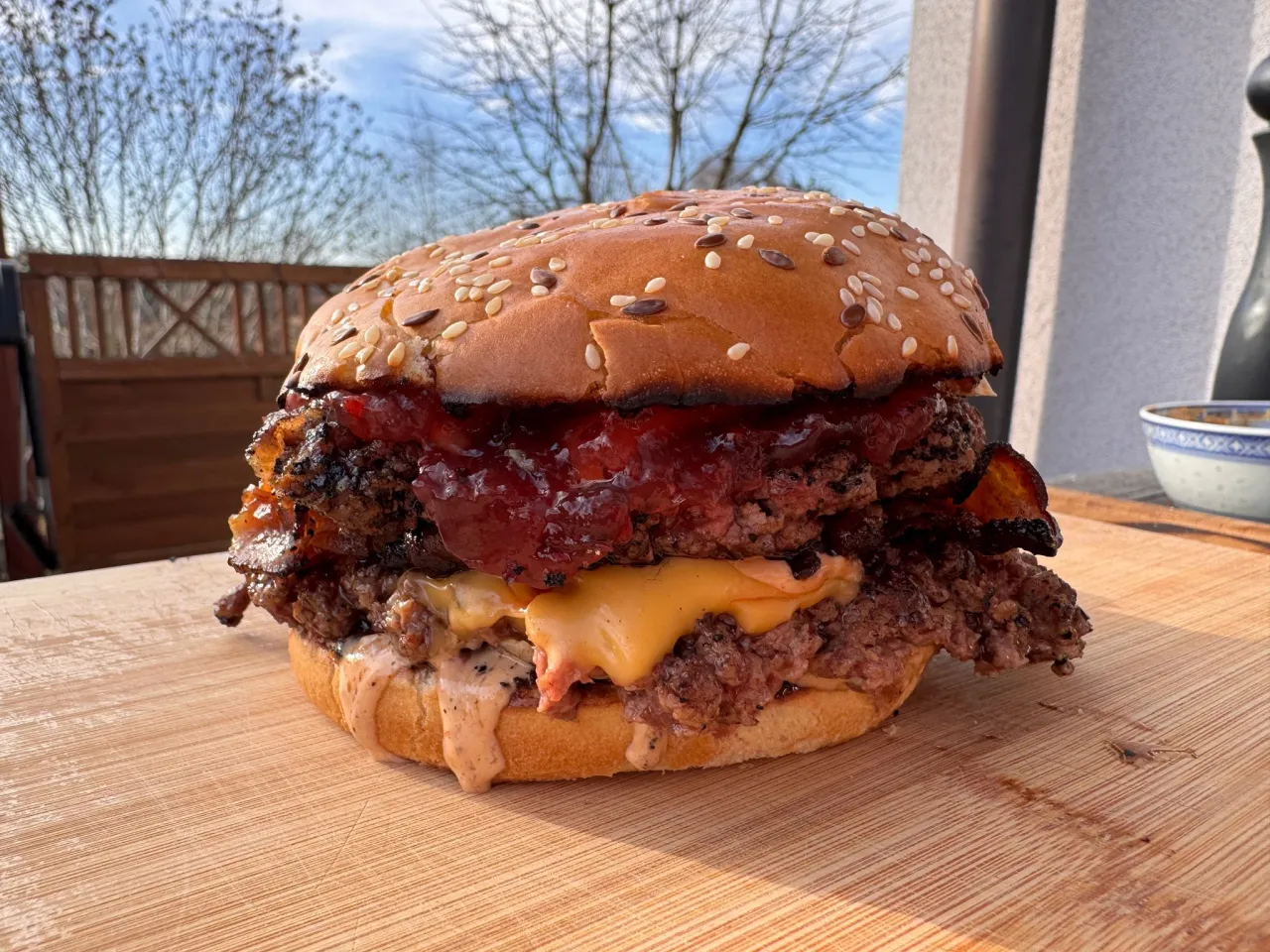 Apetyczny burger z grilla z podwójną porcją mięsa, serem, bekonem i sosem na bułce z sezamem.