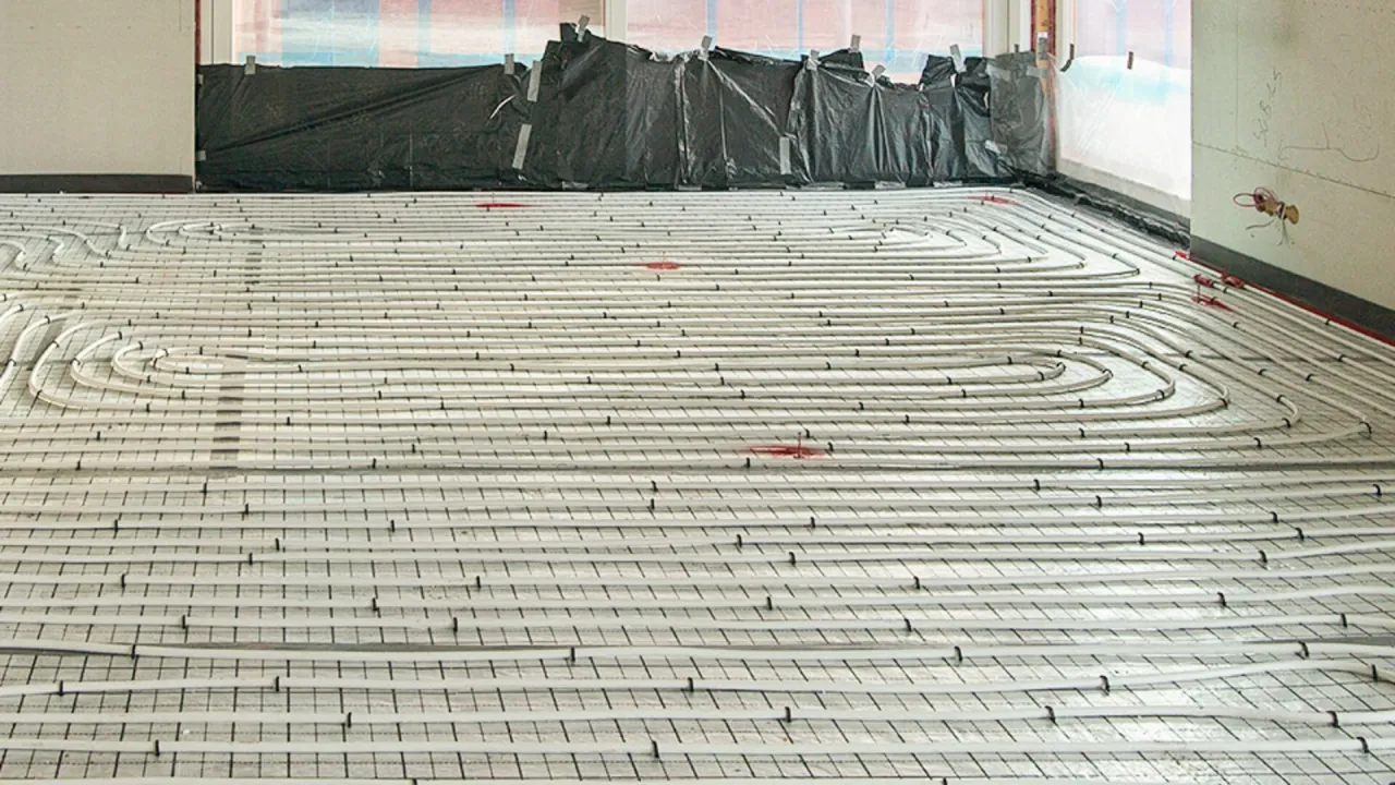 Siatka z rurkami do ogrzewania podłogowego ułożona na podłodze. To kluczowy etap, jak podłączyć ogrzewanie podłogowe.