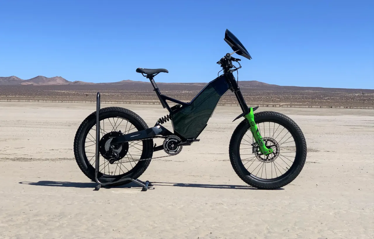 Czarny rower elektryczny z zielonymi elementami na pustyni. Dowiedz się, jak odblokować rower elektryczny, by wyruszyć na przygodę.