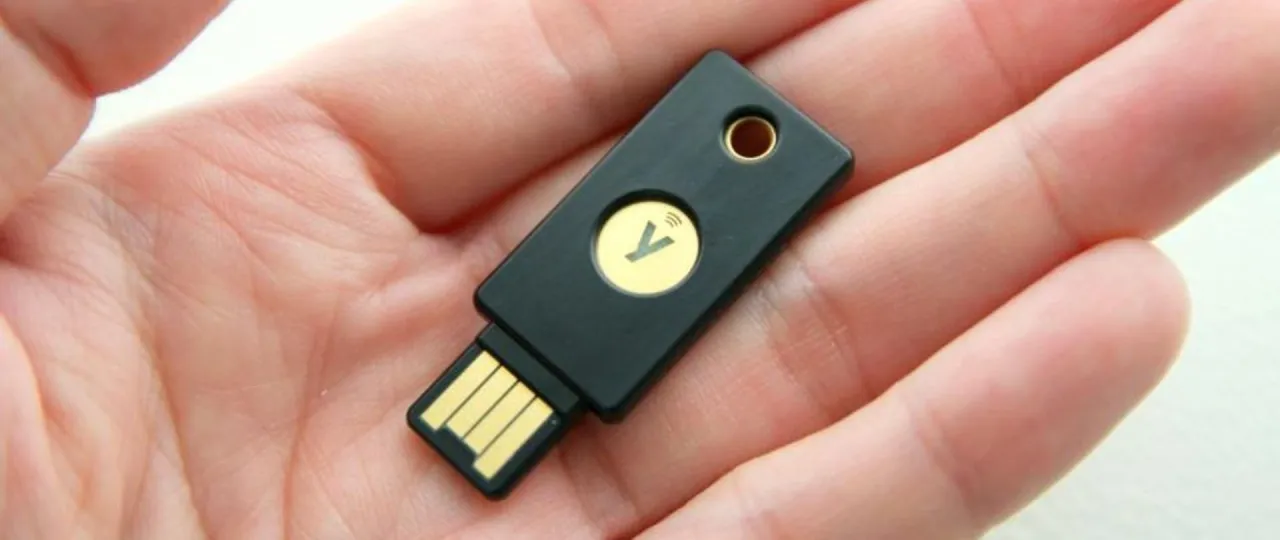 Klucz U2F co to? Mały, czarny pendrive z symbolem Y na złotym tle, trzymany w dłoni, zapewnia bezpieczeństwo.