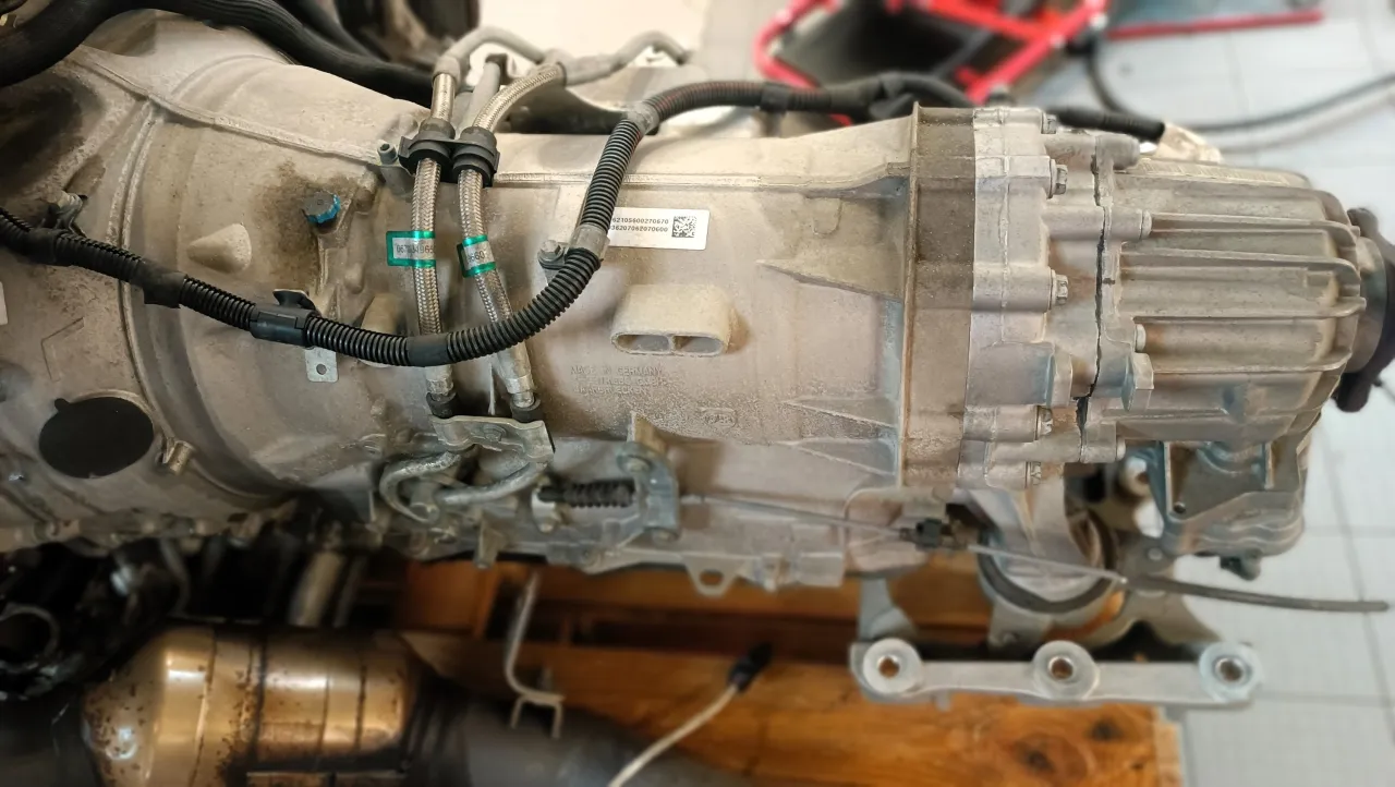 Metalowa skrzynia bieg&oacute;w w samochodzie, z widocznymi przewodami i oznaczeniami.