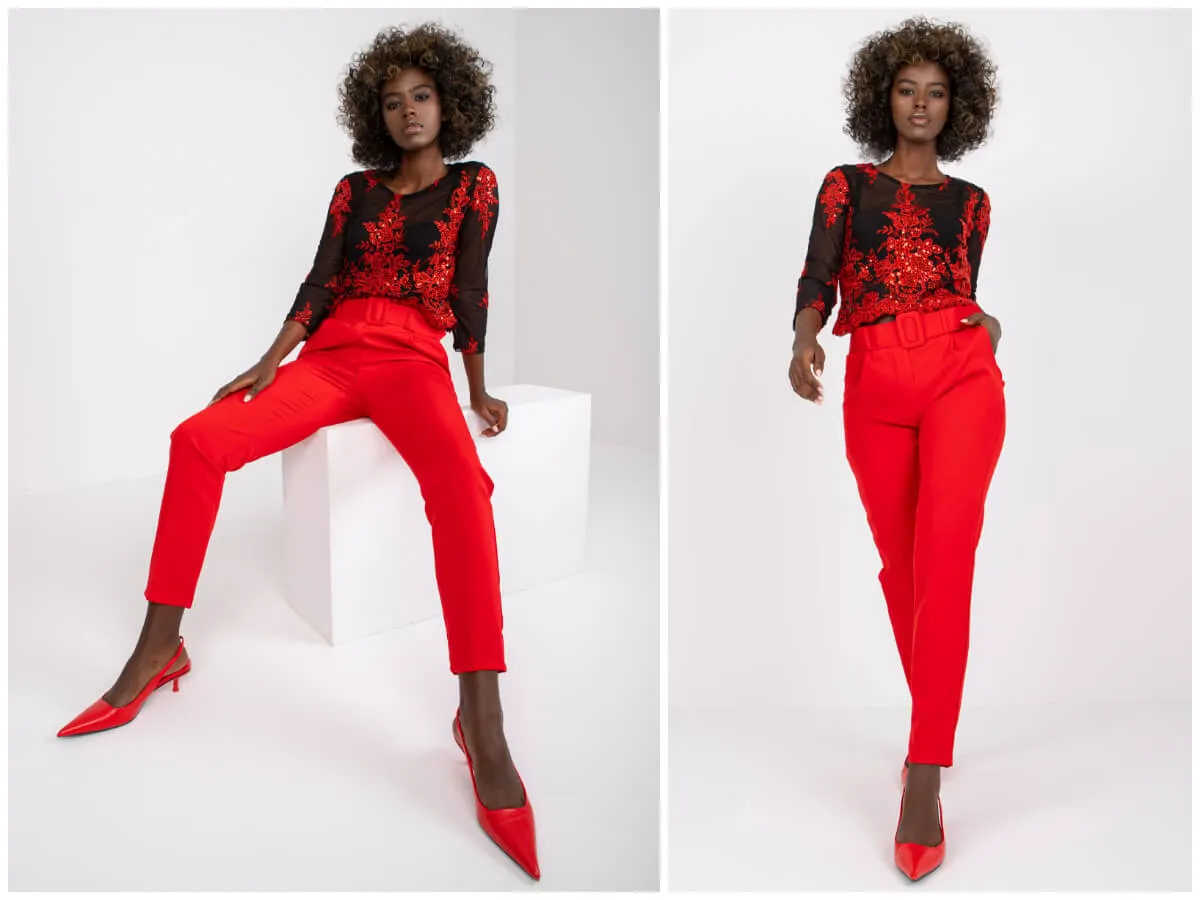 Modelka prezentuje stylizację: jaka bluzka do czerwonych spodni? Czarna, prześwitująca bluzka z czerwonymi zdobieniami i czerwone, eleganckie spodnie.