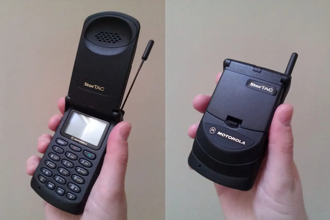 Dwa klasyczne telefony Motorola StarTAC, jedne z pierwszych modeli z klapką, w rękach użytkownika.
