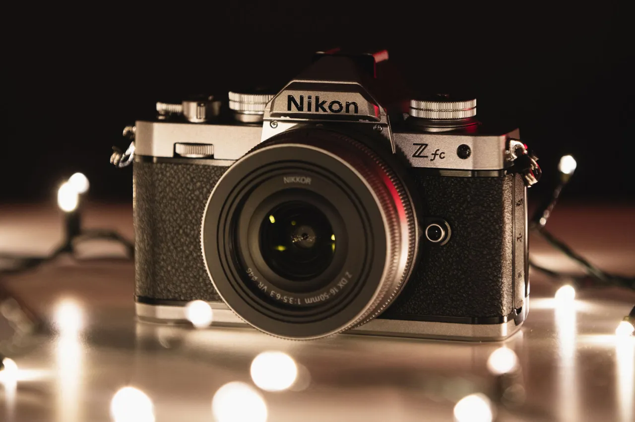 Retro aparat Nikon Z fc z obiektywem NIKKOR, otoczony świątecznymi lampkami. Zastanawiasz się, ile kosztuje aparat tej klasy?