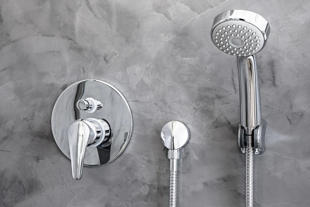 Chromowana deszczownica i bateria podtynkowa na szarej, betonowej ścianie. Poradnik: jak zamontować deszczownicę.