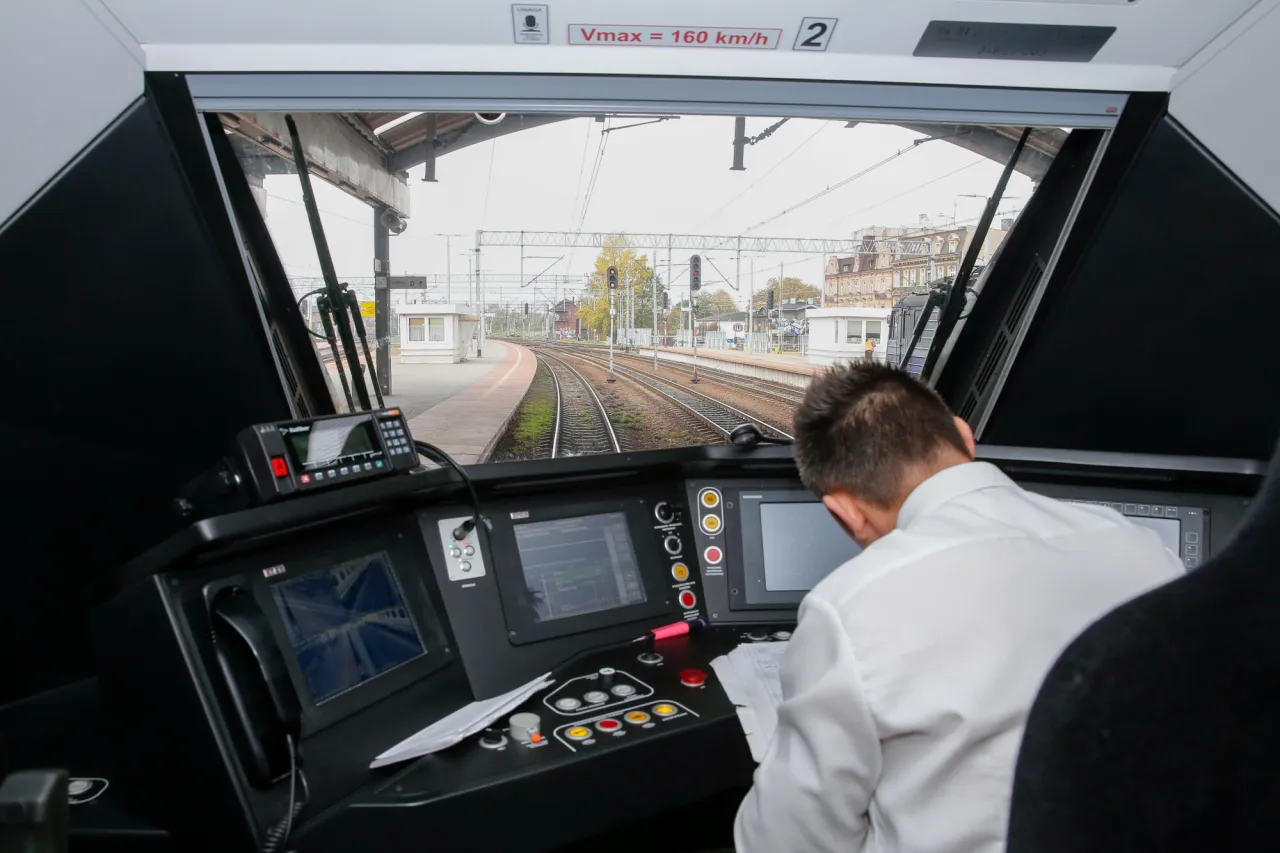 Kierowca pociągu w kabinie, przed nim pulpit sterowniczy. Zastanawiasz się, ile zarabia kierowca pociągu?